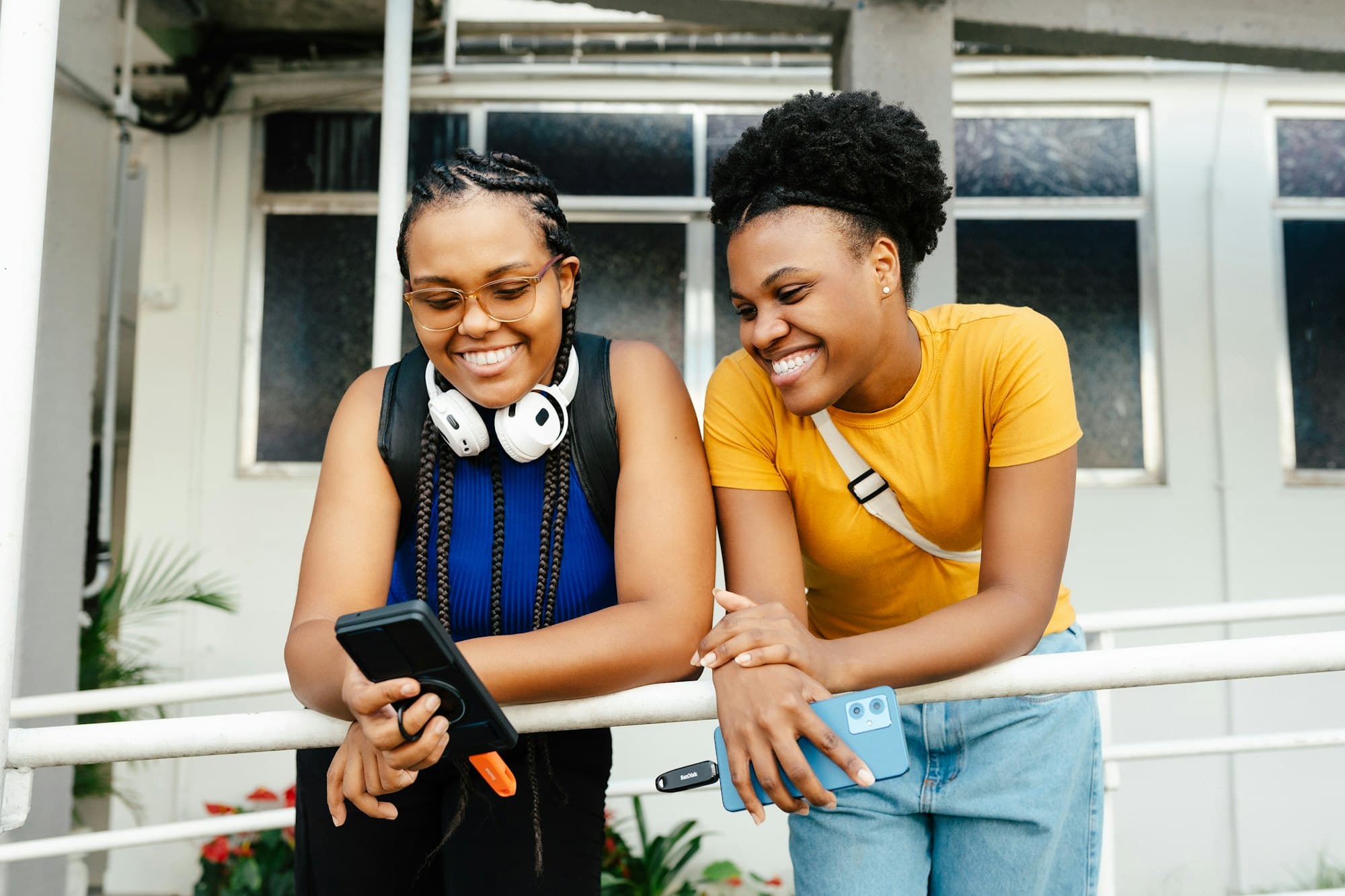 Deux étudiantes souriantes regardent un téléphone sur le campus