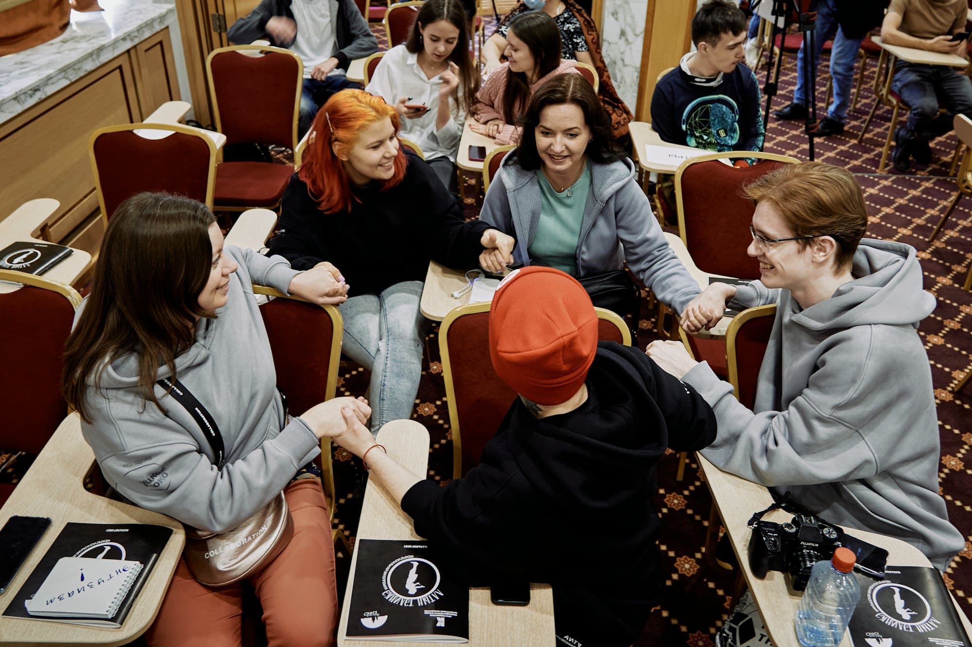 Des étudiants discutent et rient autour de tables pendant un atelier